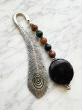 Silver feather bookmark with Amethyst and Indian Agate beads on a marble background