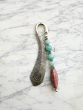 Silver feather bookmark with Amazonite and Rhodochrosite beads on a marble background