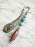 Silver feather bookmark with Amazonite and Rhodochrosite beads on a marble background