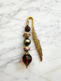 Feather bookmark with beads on a marble surface