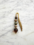 Feather bookmark with beads on a marble surface