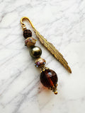 Feather bookmark with beads on a marble surface