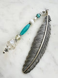 Vintage silver feather bookmark with aqua, pearl, and clear glass beads handcrafted from repurposed vintage jewellery, displayed on a marble background.