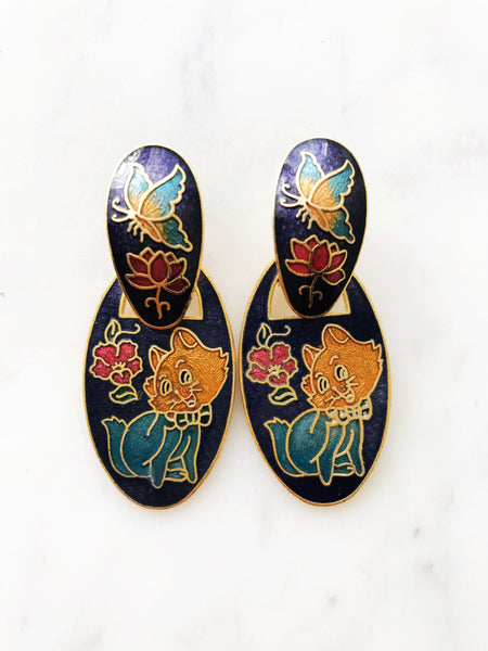 Make your ears purr with delight! These vintage Cloisonne Kitten Earrings add a fun and funky flair to any outfit, purr-fect for jazzing up a casual Friday look. Show off your love of kittens with these unique and stylish earrings!   You get 2 looks with one pair of earrings. It can be worn in 2 different ways, with the kitties on or off.  Gold Plated  52mm x 23mm