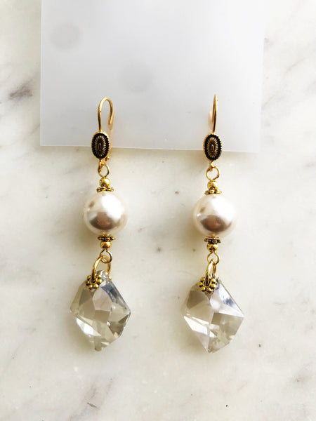 These earrings are a delightful fusion of vintage nostalgia and contemporary chic! Crafted from a once-broken strand of timeless glass pearls and paired with discontinued crystals, they carry the charm of yesteryears with a modern twist. Perfect for any occasion. Embrace the allure of bygone eras with a touch of whimsy – because true style knows no bounds!  Discontinued Crystal 6680 Cosmic Pendant 20mm Crystal (001) Silver Shade (SSHA)  Vintage Glass Pearl 10mm  Gold Plated