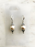 Pair of pearl earrings against a marble background