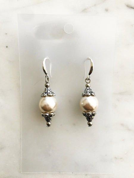 Pair of pearl earrings against a marble background