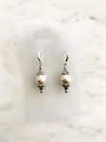Pair of pearl earrings against a marble background