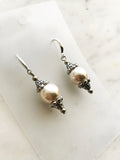 Pair of pearl earrings against a marble background