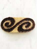 Add some vintage charm to your hair with this hand-crafted seed bead barrette. Made in France, it's a unique and stylish accessory that will elevate any hairstyle. Perfect for adding a touch of playfulness to your look! 107mm x 45mm