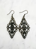 Antique Bronze Vintage Filigree Earrings. Add a touch of whimsy with our Vintage Filigree Earrings. These lightweight beauties feature intricate filigree designs for a boho vibe. Perfect for a playful and carefree look.
Lightweight brass metal stampings with an antique bronze patina.
72mm from the top of the ear hook x 30mm