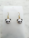 Enamel Panda earrings on a marble background