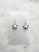 Enamel Panda earrings on a marble background