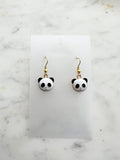 Enamel Panda earrings on a marble background