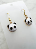 Panda-shaped earrings on a white card with marble background