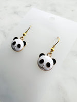 Panda-shaped earrings on a white card with marble background