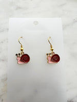 Snail-shaped earrings on a white card with a marble background