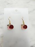 Snail-shaped earrings on a white card with a marble background