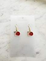 Snail-shaped earrings on a white card with a marble background