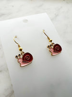 Snail-shaped earrings on a white card with a marble background