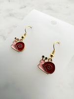 Snail-shaped earrings on a white card with a marble background
