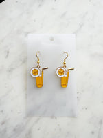 Pair of kawaii earrings with a cocktail design on a marble background