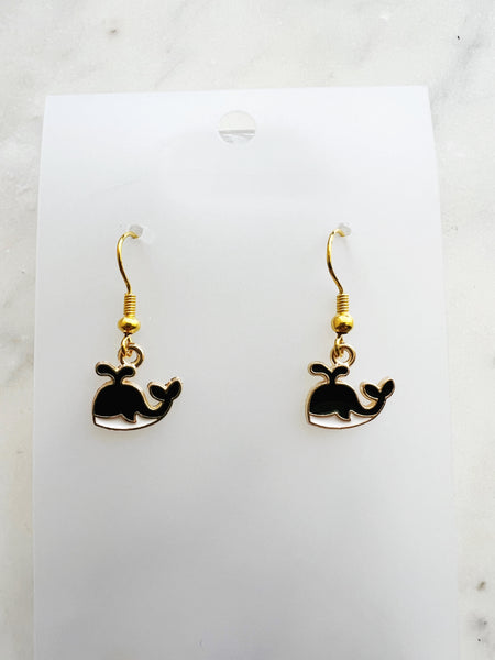 Kawaii Black whale-shaped earrings on a white card with a marble background