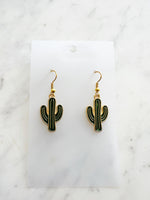 Kawaii Cactus-shaped earrings on a white card with a marble background