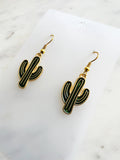 Kawaii Cactus-shaped earrings on a white card with a marble background