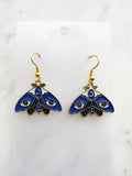 Kawaii Blue moth with evil eye earrings on a white marble background