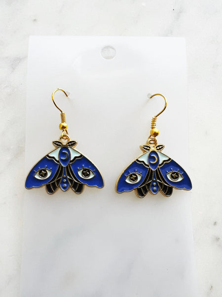 Kawaii Blue moth with evil eye earrings on a white marble background