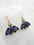 Kawaii Blue moth with evil eye earrings on a white marble background