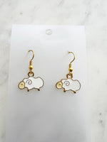 Kawaii Sheep-shaped earrings on a white card with a marble background