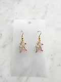 Pink Christmas Reindeer-shaped earrings on a white card with a marble background