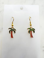 Kawaii Palm tree earrings on a white card with a marble background