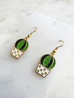 Kawaii Cactus-shaped earrings on a white card with a marble background