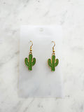 Kawaii Cactus-shaped earrings on a white card with a marble background