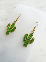 Kawaii Cactus-shaped earrings on a white card with a marble background