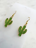 Kawaii Cactus-shaped earrings on a white card with a marble background