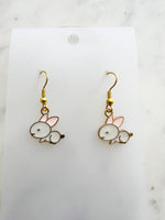 Pair of Kawaii bunny-shaped earrings on a white card with a marble background