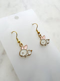 Pair of Kawaii bunny-shaped earrings on a white card with a marble background
