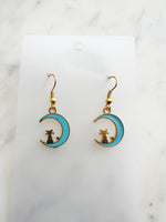 Kawaii Earrings with cat and moon design on a white card with a marble surface