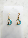 Kawaii Earrings with cat and moon design on a white card with a marble surface