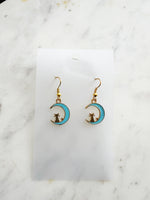 Kawaii Earrings with cat and moon design on a white card with a marble surface
