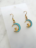 Kawaii Earrings with cat and moon design on a white card with a marble surface