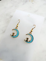 Kawaii Earrings with cat and moon design on a white card with a marble surface