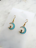 Kawaii Earrings with cat and moon design on a white card with a marble surface