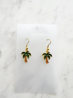Kawaii Palm tree earrings on a white card with a marble background