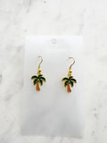 Kawaii Palm tree earrings on a white card with a marble background