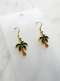Kawaii Palm tree earrings on a white card with a marble background